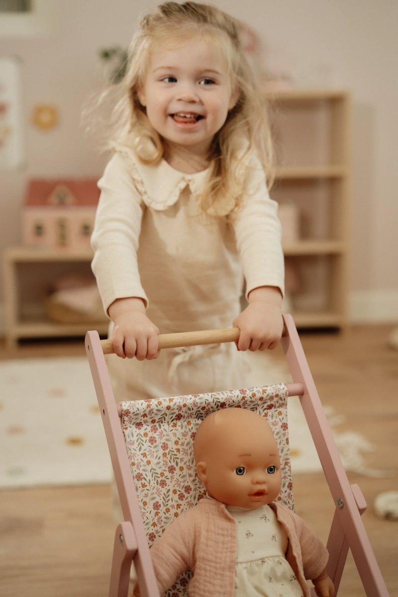 Kind schiebt den Little Dutch Holz-Puppenbuggy mit Puppe